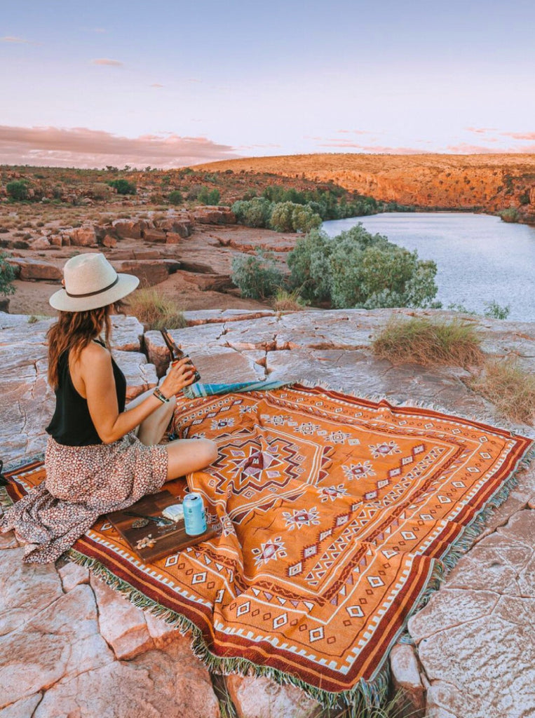 Girl in Aussie Outback, The Kimberley Region Western Australia on a boho picnic rug inspired by the sun burnt landscape. 